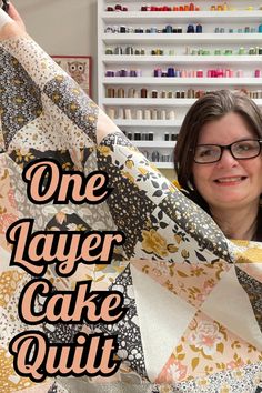 a woman holding up a piece of fabric with the words one layer cake quilt on it