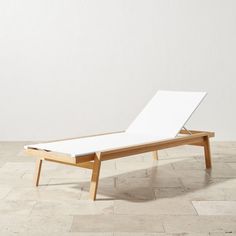 an empty chaise lounger on a tiled floor in front of a white wall