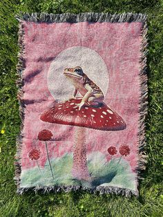 a blanket with a frog sitting on top of a mushroom