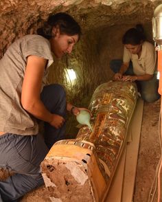 two women are working on an object in a cave