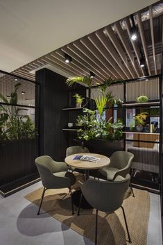 an office with black walls and plants on the wall, chairs around a round table