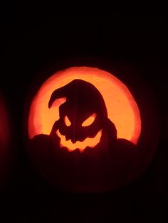 two pumpkins with faces carved into them in front of a black background, one is orange and the other is red