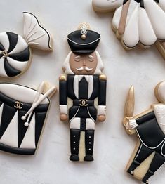 decorated cookies in the shape of soldiers and sailors on a white tablecloth with gold trimmings