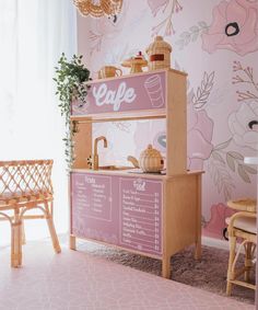 a pink and white wallpapered room with a cafe sign on the counter next to a wooden bench