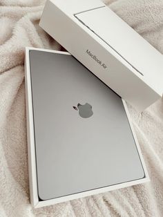 an apple macbook air is sitting on a bed with its box open and it's inside