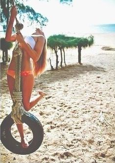 a woman on a tire swing in the sand