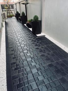 an empty walkway with black planters on each side and white walls in the background