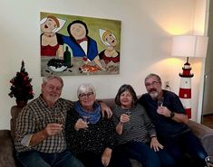 three people sitting on a couch with wine glasses in their hands and a painting behind them