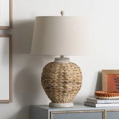 a table lamp sitting on top of a blue dresser next to a painting and framed pictures