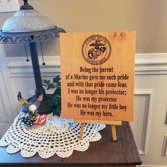 a wooden sign sitting on top of a table next to a lamp and doily