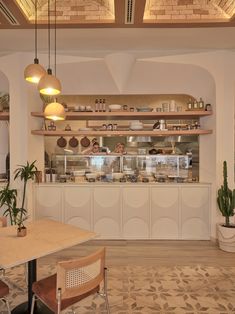 the interior of a restaurant with wooden tables and chairs, potted plants, and shelves