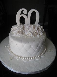 a close up of a cake on a table with flowers and pearls around the edges