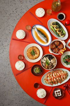 a red table topped with plates and bowls filled with food