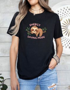 Embrace the slow and steady lifestyle with our adorable Sleepy Sloth T-shirt! This cozy tee features a charming sloth design that's perfect for lazy days and relaxed vibes. Whether you're lounging at home, running errands, or hanging out with friends, this T-shirt is sure to be your new favorite. It's the perfect gift for sloth lovers, animal enthusiasts, and anyone who appreciates a laid-back look.  .: Made with 100% Airlume combed and ring-spun cotton, a lightweight fabric that is easy to laye Casual Cartoon Print T-shirt For Loungewear, Cute T-shirt With Slogan For Lounging, Sloth Design, Slow And Steady, Sloth Lovers, Lazy Days, Prism Color, Energy Saving, Tee Design