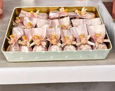 there are many small pink candies in a box on the table next to some candles