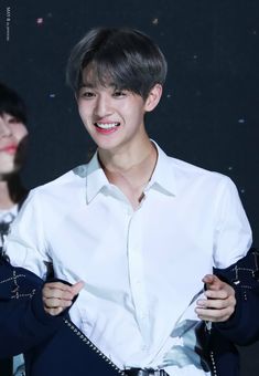 the young man is smiling while wearing a white shirt