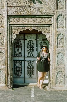 a woman standing in front of an ornate door