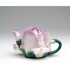 a pink and white flower sitting inside of a teacup on a tablecloth covered surface