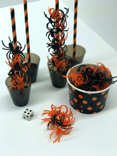 black and orange cupcakes with candles in them on a white tablecloth next to some halloween decorations