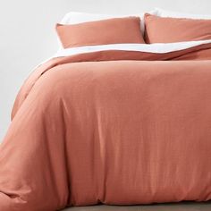 a bed with an orange comforter and two pillows