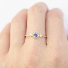 a woman's hand holding a ring with a tan and blue stone on it