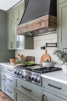 a stove top oven sitting inside of a kitchen next to green cupboards and drawers