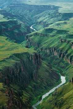 an aerial view of the green mountains and river in the valley, with water flowing between them