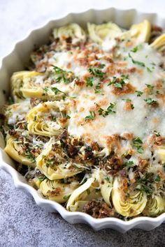 a white dish filled with pasta covered in sauce and parmesan cheese sprinkled on top