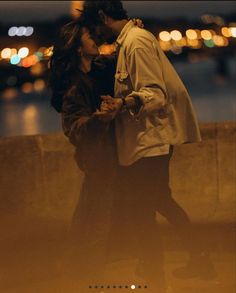 a man and woman standing next to each other in front of a body of water