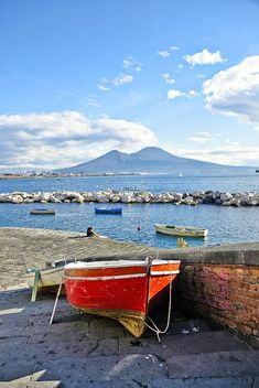 there is a red boat sitting on the shore