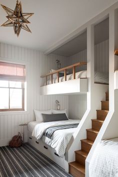 a bedroom with bunk beds and stairs leading up to the second floor, while another bed is on the other side of the room