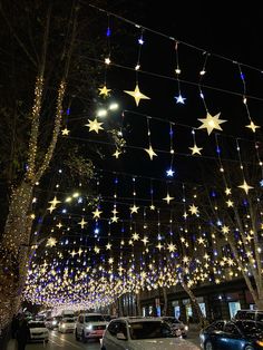 cars parked on the street with christmas lights strung above them