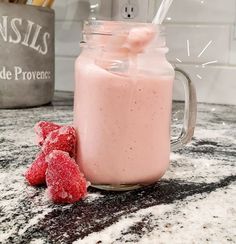 a jar filled with pink liquid next to some strawberries