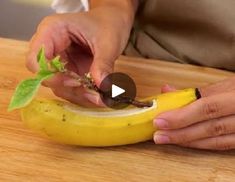 a person cutting up a banana on top of a wooden table