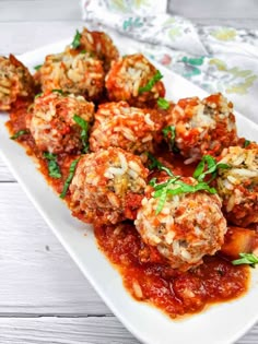 meatballs covered in marinara sauce and parsley on a white serving platter