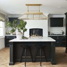 a kitchen with two stools in front of the island and an oven above it