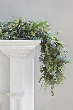 an arrangement of greenery hangs from the top of a pedestal