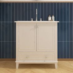 a bathroom with blue tiles and a white cabinet in the corner, next to a mirror