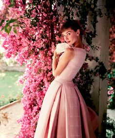 a woman in a pink dress standing next to flowers