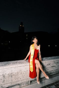 a woman in a red and yellow dress leaning on a wall