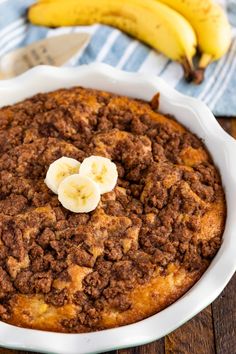 a close up of a pie in a pan with bananas on the table behind it