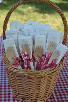 a wicker basket filled with forks and spoons on top of a checkered table cloth