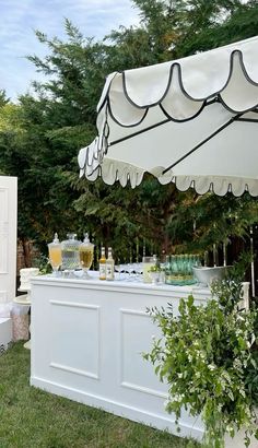 an outdoor bar with umbrellas and drinks on the table in front of some trees