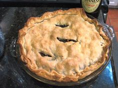 a pie sitting on top of a counter next to a bottle of wine and a knife