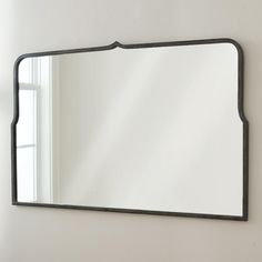 a large mirror hanging on the wall above a sink in a room with white walls