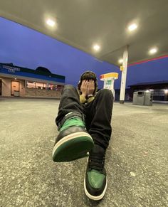 a man sitting in the middle of a parking lot with his feet up to his face