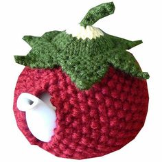 a red knitted apple with a green leaf on it's side and a white cup holder in the middle