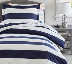 a bed with blue and white striped comforter in a bedroom next to a night stand