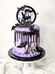 a purple and black birthday cake decorated with spooky icing, bats and a hand