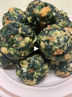 spinach balls stacked on top of each other on a white plate with pink trim